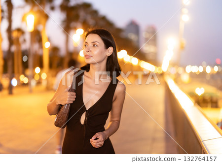 Young woman standing at parapet at Barceloneta beach in summer evening Young woman standing at parapet at Barceloneta beach in summer evening 132764157