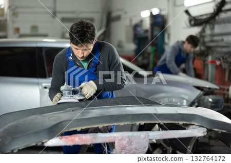 Man auto mechanic polishes body parts by car buffer polisher machine tool Man auto mechanic polishes body parts by car buffer polisher machine tool 132764172