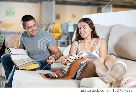 Husband and wife choose color and material for future sofa according to the samples of materials in furniture store 132764182