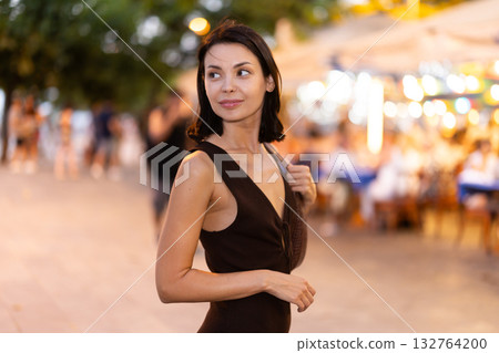 In evening, smiling girl walks around old city district Barceloneta, in vicinage of Citadel Park 132764200