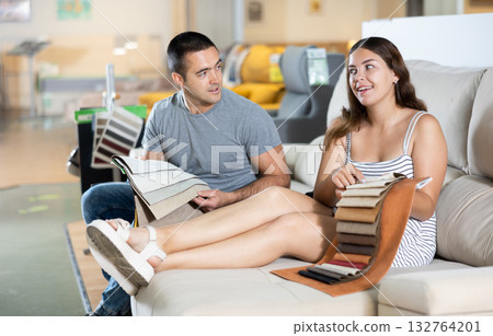 Smiling woman and man choosing upholstery for sofa in furnishing store 132764201