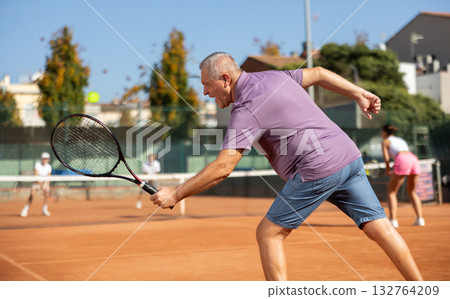 Elderly man playing tennis 132764209