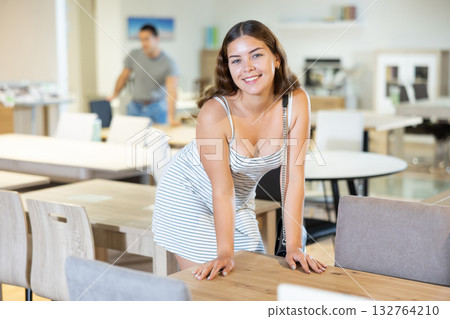 Smiling young girl choosing dining table for home in store Smiling young girl choosing dining table for home in store 132764210