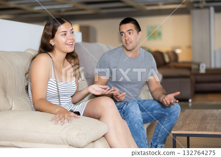 Young woman with husband testing sofa in furniture salon 132764275