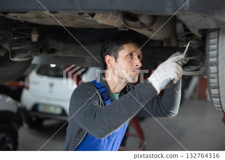 Service station man employee works in repair box, department 132764316
