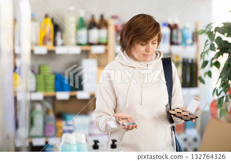 Store visitor woman purchases in household chemicals department, choose eye shadow pallet Store visitor woman purchases in household chemicals department, choose eye shadow pallet 132764326