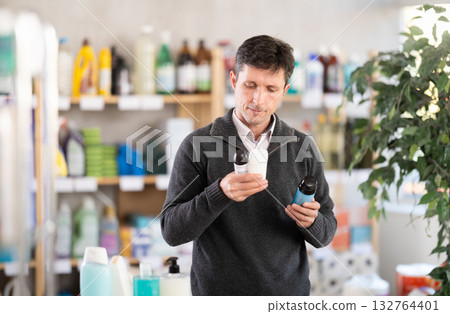 Middle-aged man choosing some deodorant at department store Middle-aged man choosing some deodorant at department store 132764401