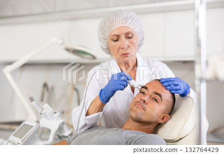 Man on facial skin rejuvenation procedures using various hardware procedures in clinic 132764429