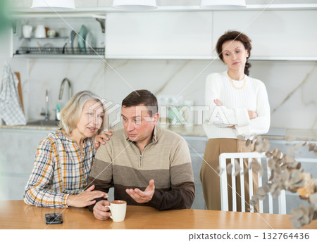 Family members quarreling in the kitchen and old woman trying to calm angry man 132764436