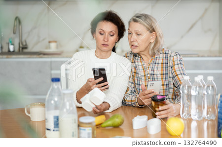 Two careful women scanning different products using their smartphones 132764490