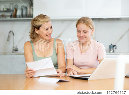 Cheerful woman with teenage daughter reading letter together 132764517