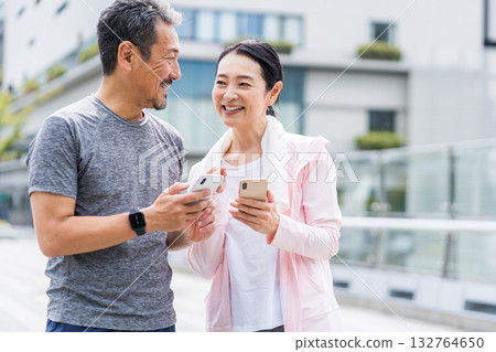 一對夫婦一邊慢跑一邊看智慧型手機 一對夫婦一邊慢跑一邊看智慧型手機 132764650