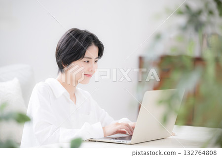 畫面中一位女性家庭主婦或設計師正在家中遠距辦公,房間裡擺放著綠植,她正在使用電腦。 畫面中一位女性家庭主婦或設計師正在家中遠距辦公,房間裡擺放著綠植,她正在使用電腦。 132764808