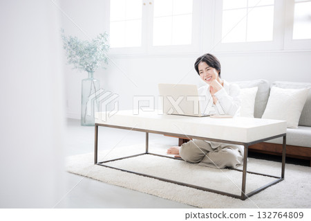 一位女性家庭主婦或設計師在家遠距辦公,房間裡擺放著綠植,她正在使用電腦,照片為全身照。 一位女性家庭主婦或設計師在家遠距辦公,房間裡擺放著綠植,她正在使用電腦,照片為全身照。 132764809