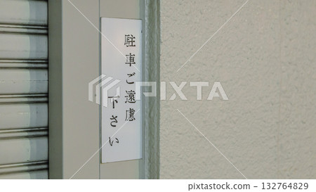 一塊寫著「請勿停車」的標誌牌和建築物的外牆 132764829