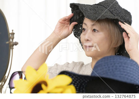 Senior women choosing hats and sunglasses to protect themselves from UV rays when going out in the summer 132764875