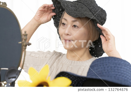 Senior women choosing hats and sunglasses to protect themselves from UV rays when going out in the summer Senior women choosing hats and sunglasses to protect themselves from UV rays when going out in the summer 132764876