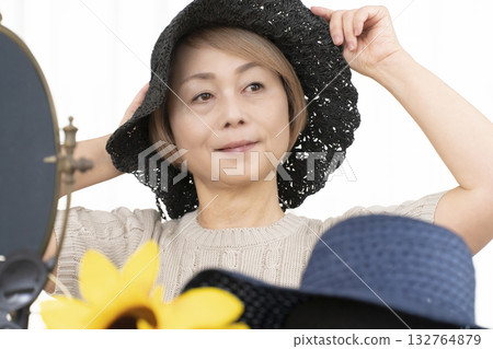 Senior women choosing hats and sunglasses to protect themselves from UV rays when going out in the summer Senior women choosing hats and sunglasses to protect themselves from UV rays when going out in the summer 132764879