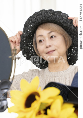 Senior women choosing hats and sunglasses to protect themselves from UV rays when going out in the summer 132764884
