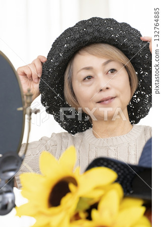Senior women choosing hats and sunglasses to protect themselves from UV rays when going out in the summer Senior women choosing hats and sunglasses to protect themselves from UV rays when going out in the summer 132764885