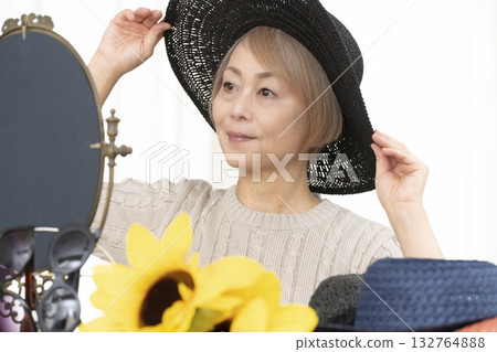 夏季外出時，老年婦女會選擇帽子和太陽眼鏡來保護自己免受紫外線傷害。 132764888