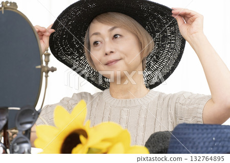 Senior women choosing hats and sunglasses to protect themselves from UV rays when going out in the summer Senior women choosing hats and sunglasses to protect themselves from UV rays when going out in the summer 132764895