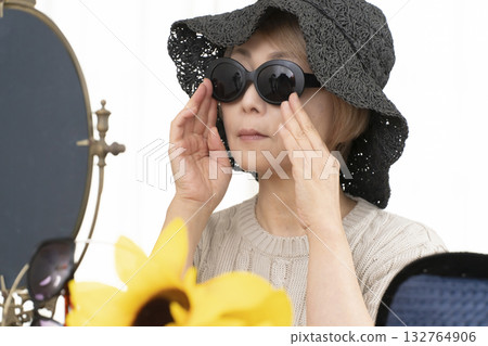 Senior women choosing hats and sunglasses to protect themselves from UV rays when going out in the summer Senior women choosing hats and sunglasses to protect themselves from UV rays when going out in the summer 132764906
