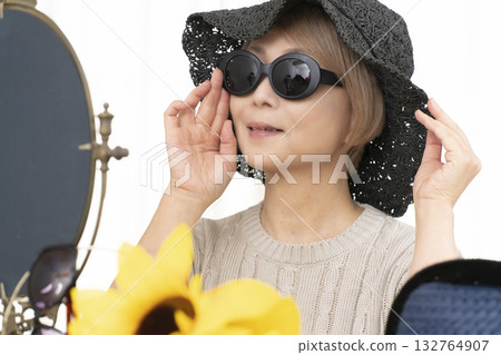 Senior women choosing hats and sunglasses to protect themselves from UV rays when going out in the summer Senior women choosing hats and sunglasses to protect themselves from UV rays when going out in the summer 132764907