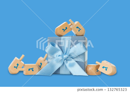 Dreidels circle a gift box tied with a blue ribbon 132765323