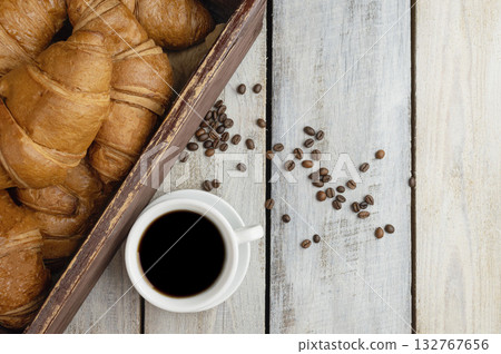 croissant and black coffee in white cup for breakfast. Flat lay. Top view with copy space. Cup and coffee grains. 132767656