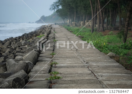 Massive concrete tetrapods along the seashore walkway to prevent waves coming to shore Massive concrete tetrapods along the seashore walkway to prevent waves coming to shore 132768447