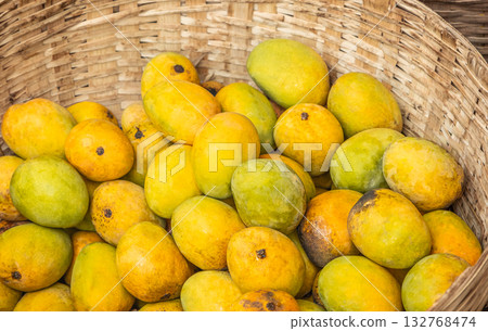 Fresh yellow mangoes in wicker basket. Tropical fruit harvest display Fresh yellow mangoes in wicker basket. Tropical fruit harvest display 132768474