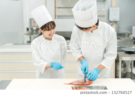 身穿廚師服的男女工作人員煮魚(廚師、廚師、菜市場、食物加工) 身穿廚師服的男女工作人員煮魚(廚師、廚師、菜市場、食物加工) 132768527
