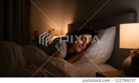 Young woman peacefully sleeping in cozy bedroom with soft lighting and serene ambiance Young woman peacefully sleeping in cozy bedroom with soft lighting and serene ambiance 132769257