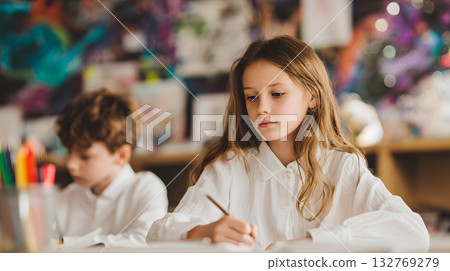 Young girl and boy engaged in creative drawing activity in a colorful classroom environment 132769279
