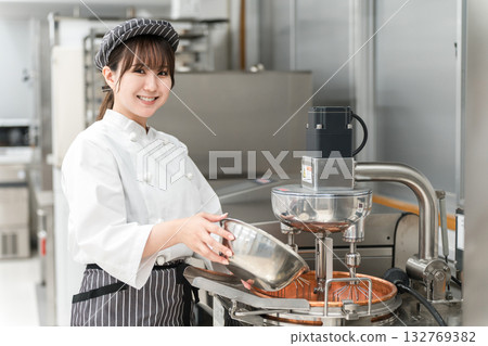 A female pastry chef using a mixer in the kitchen 132769382