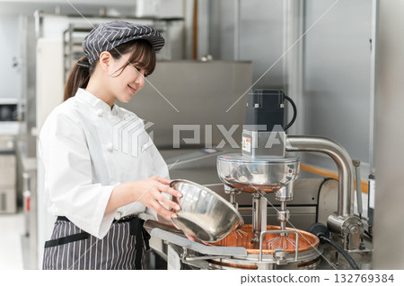 一位女糕點師正在廚房使用攪拌機。 132769384