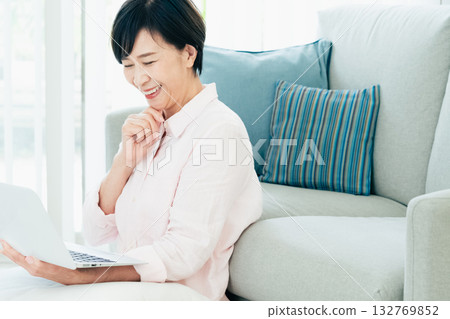 A middle-aged woman operating a computer in the living room A middle-aged woman operating a computer in the living room 132769852