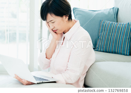 A middle-aged woman operating a computer in the living room A middle-aged woman operating a computer in the living room 132769858