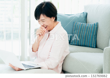A middle-aged woman operating a computer in the living room A middle-aged woman operating a computer in the living room 132769862