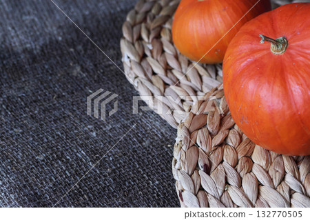 Two orange pumpkins lying on placemats. On a rough linen burlap background. 132770505