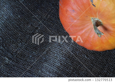 Orange pumpkin with a tail. On a rough linen burlap background. Shot from above. 132770513