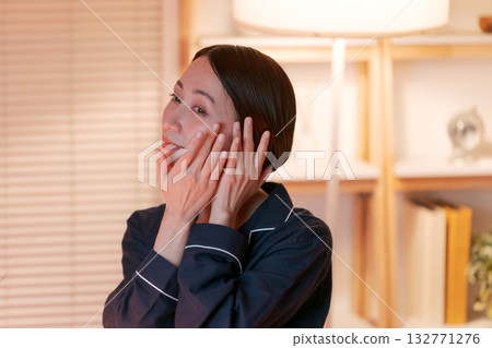一位女士晚上在房間裡做護膚。 132771276