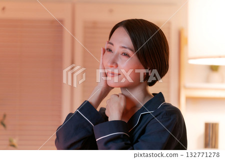 一位女士晚上在房間裡做護膚。 132771278