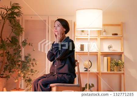 A woman doing skin care in her room at night 132771285