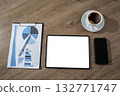 A flat lay workspace shows a tablet with a blank white screen beside a business report, a smartphone and a coffee cup, suitable for UX presentations and app mockups. 132771747