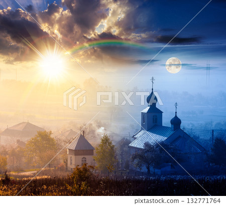 old church in the village in autumn. day and night time change concept. view of countryside landscape from a hill in haze with sun and moon. empty rural fields. duality and transition template 132771764