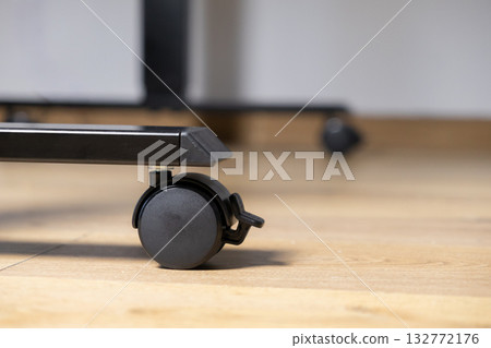 Sleek black furniture caster wheel with integrated brake on a modern metal leg, offering adaptable mobility and stability for contemporary home and office furniture 132772176