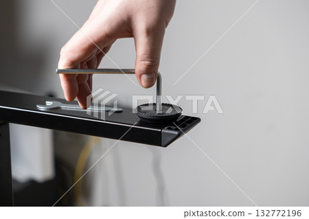 Human hand using an Allen wrench to adjust furniture leg during assembly, representing practical DIY skills, home repair, and product installation 132772196