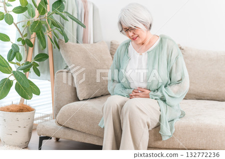 A senior woman with gray and silver hair suffering from stomach pain A senior woman with gray and silver hair suffering from stomach pain 132772236